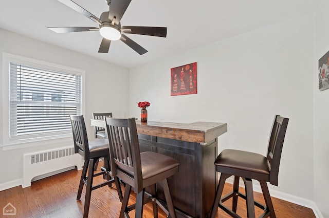 dining room with baseboards, ceiling fan, radiator heating unit, and wood finished floors