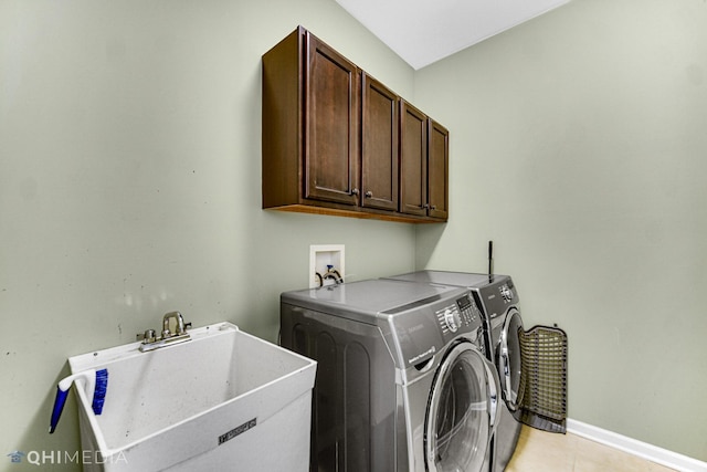 laundry room featuring baseboards, light tile patterned floors, washer and dryer, cabinet space, and a sink