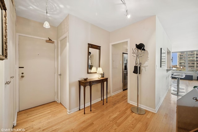 foyer featuring light wood-style floors, baseboards, and track lighting