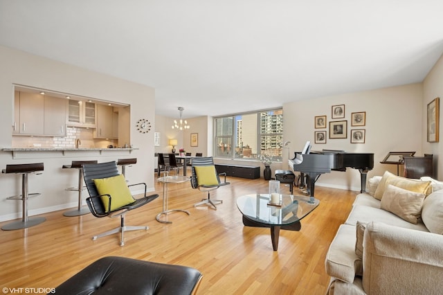 living area featuring light wood finished floors, baseboards, and a notable chandelier