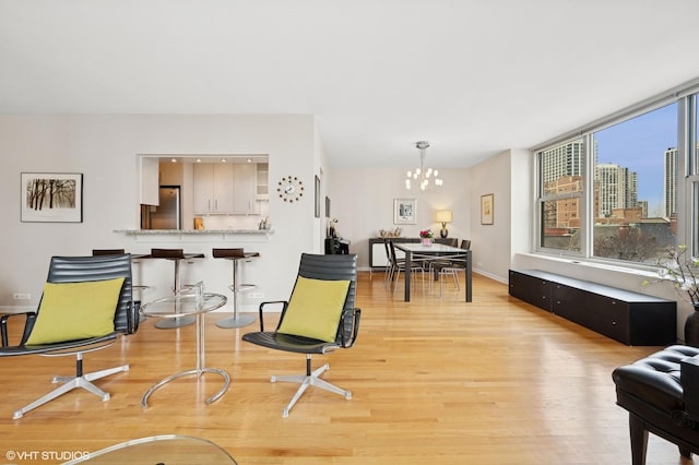 sitting room featuring light wood-style flooring, a chandelier, a city view, and baseboards