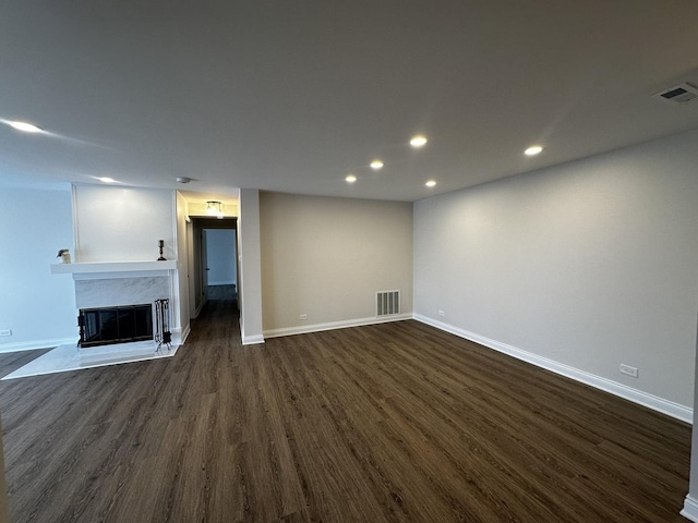 below grade area with baseboards, visible vents, dark wood-type flooring, and a glass covered fireplace