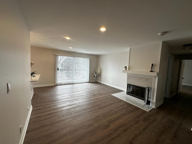 unfurnished living room with dark wood-style flooring, a premium fireplace, recessed lighting, and baseboards