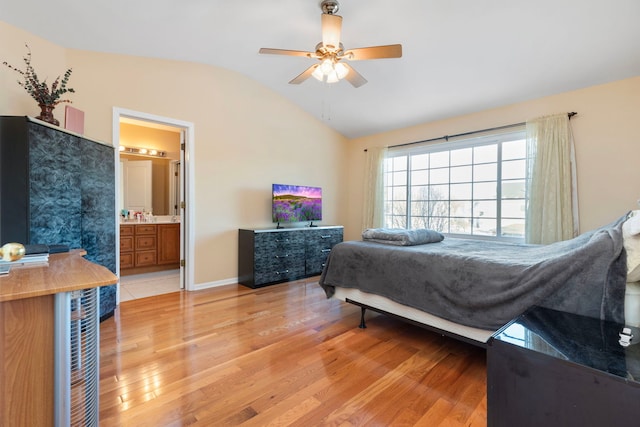 bedroom with lofted ceiling, light wood-style flooring, a ceiling fan, connected bathroom, and baseboards