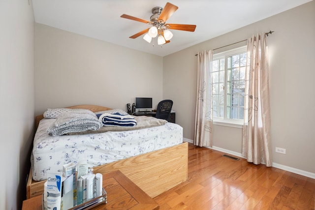 bedroom featuring a ceiling fan, wood finished floors, visible vents, and baseboards