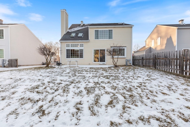 snow covered property with a chimney and fence