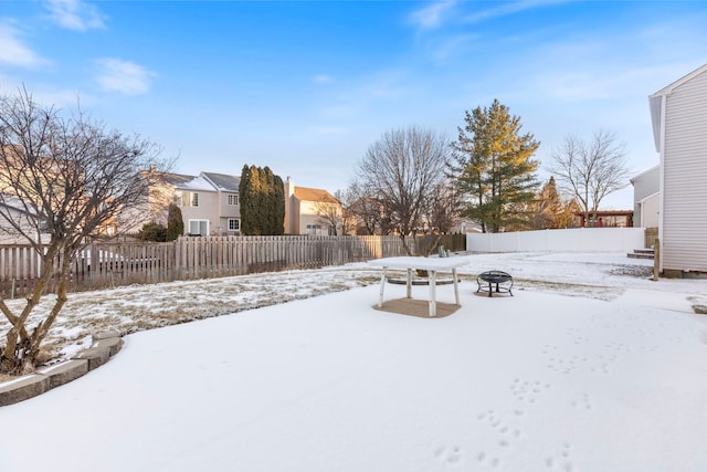 yard layered in snow with an outdoor fire pit, fence, and a residential view