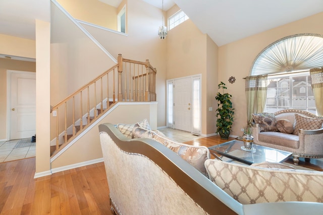 living area with light wood-type flooring, baseboards, a high ceiling, and stairway