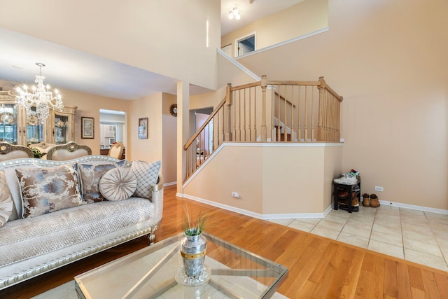 living room featuring a notable chandelier, a high ceiling, wood finished floors, baseboards, and stairway