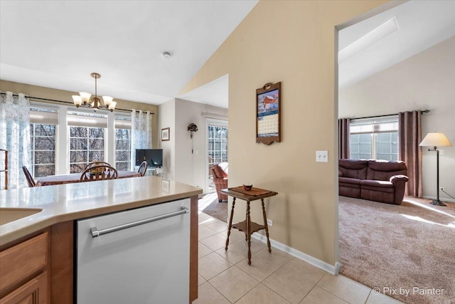 kitchen with a healthy amount of sunlight, light carpet, stainless steel dishwasher, and light tile patterned floors