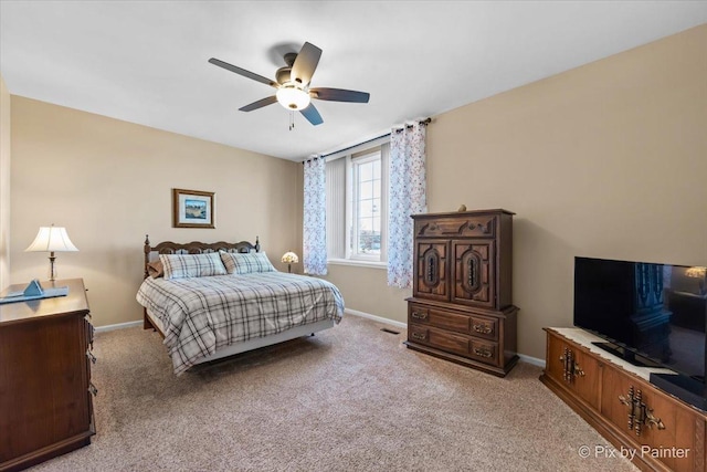 bedroom with a ceiling fan, light carpet, and baseboards