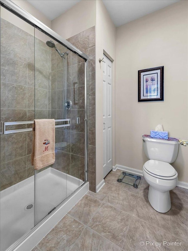 full bathroom with toilet, a shower stall, and baseboards