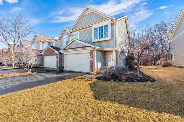 view of front facade with aphalt driveway, a front yard, brick siding, and an attached garage