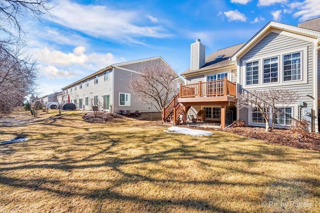 back of property featuring stairway, a chimney, a wooden deck, and a lawn