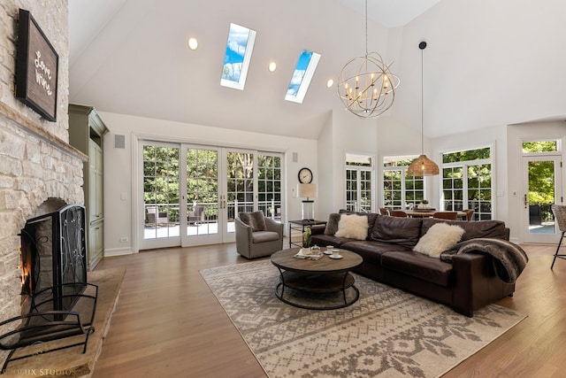 living area featuring a wealth of natural light, a stone fireplace, light wood-style flooring, and french doors