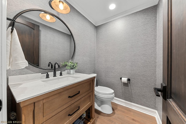 bathroom featuring toilet, wood finished floors, crown molding, baseboards, and vanity