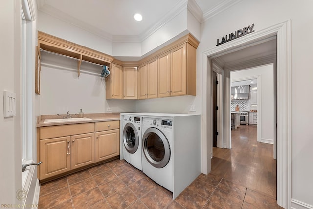 washroom with a sink, cabinet space, crown molding, and washer and dryer