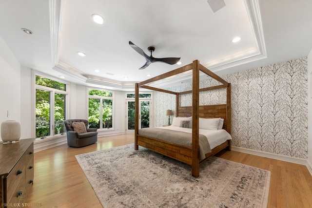 bedroom with a raised ceiling, light wood-style flooring, and ornamental molding