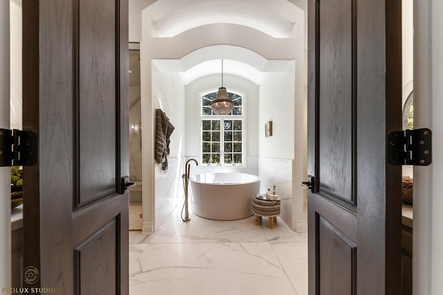 full bathroom with wainscoting, marble finish floor, and a freestanding bath