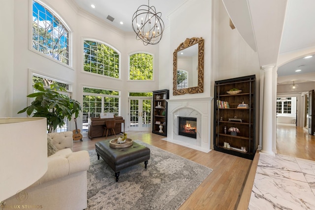 living area featuring visible vents, decorative columns, arched walkways, a high end fireplace, and crown molding