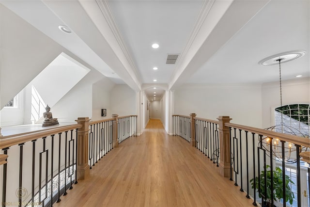 hallway featuring a chandelier, visible vents, crown molding, and wood finished floors