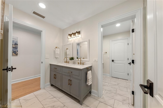 bathroom with visible vents, baseboards, double vanity, marble finish floor, and a sink