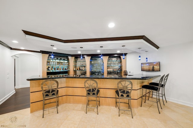 bar with arched walkways, crown molding, bar area, and a tray ceiling