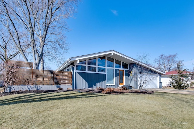 mid-century home with driveway, an attached garage, and a front yard