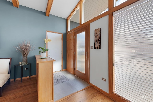 foyer entrance with beamed ceiling, wood finished floors, and baseboards