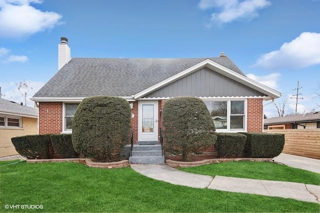 view of front of house with brick siding, fence, and a front yard