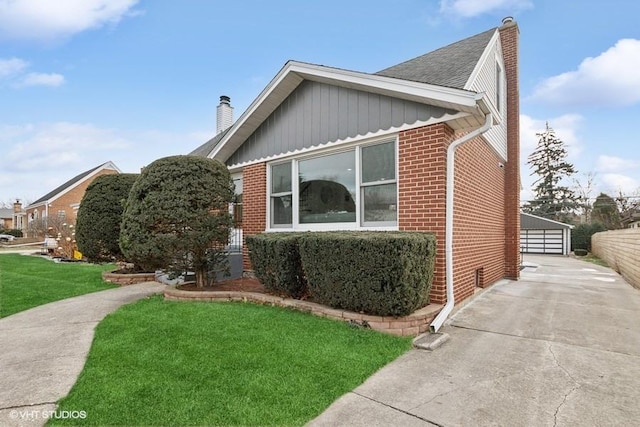 view of side of home featuring board and batten siding, brick siding, a lawn, and a chimney