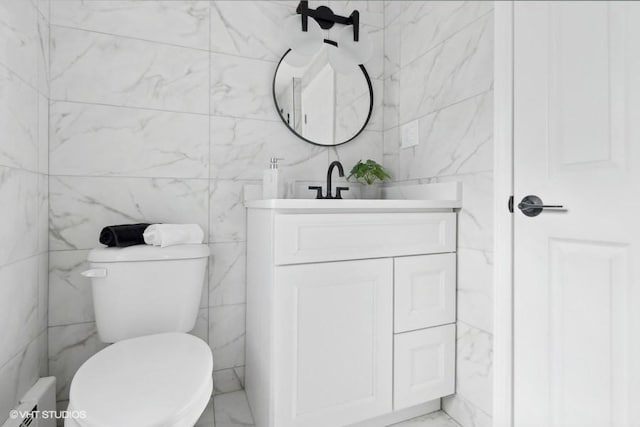 half bath with a baseboard radiator, marble finish floor, vanity, and toilet