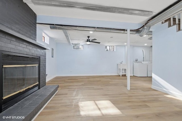 basement with a brick fireplace, baseboards, washer and clothes dryer, and light wood-style floors