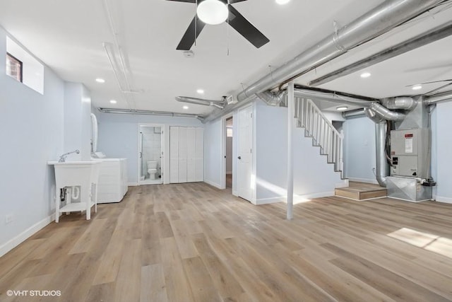 unfinished below grade area featuring light wood-style flooring, a sink, baseboards, stairs, and washer / clothes dryer