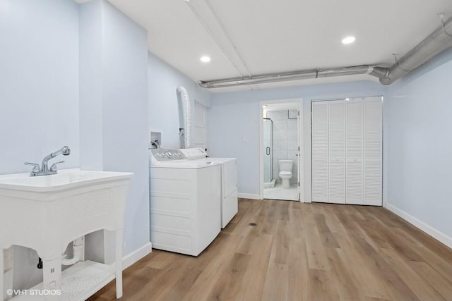 washroom featuring baseboards, laundry area, light wood-style floors, and washer and dryer