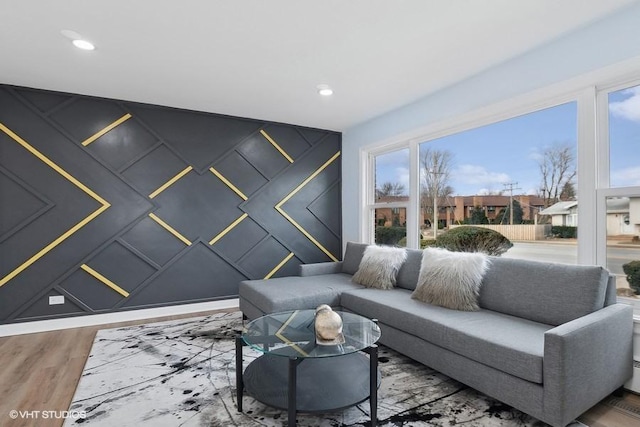 living area featuring an accent wall, wood finished floors, and recessed lighting