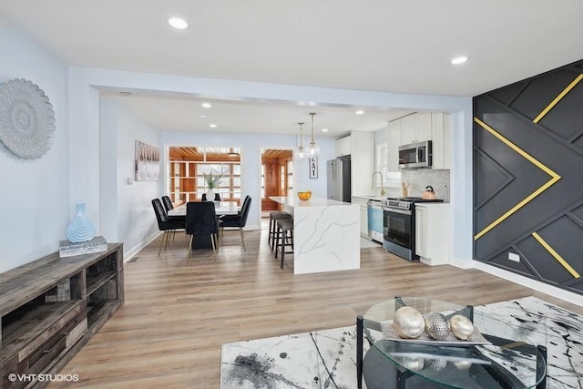 living area featuring baseboards, light wood-style flooring, and recessed lighting