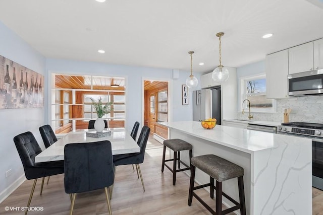 dining area with light wood-type flooring, a wealth of natural light, baseboards, and recessed lighting