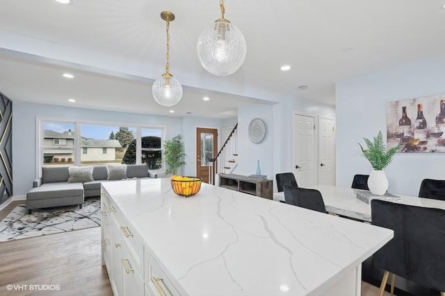 kitchen with light stone counters, recessed lighting, white cabinetry, open floor plan, and hanging light fixtures