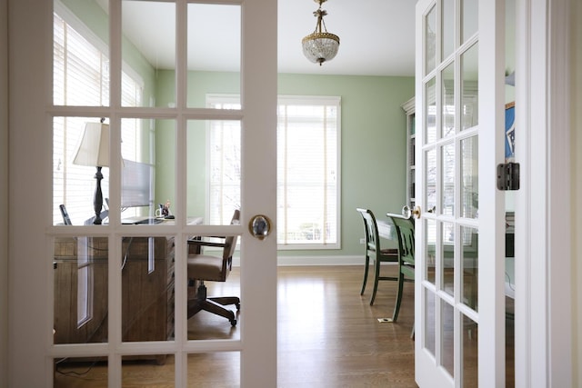 dining area with french doors, baseboards, and wood finished floors