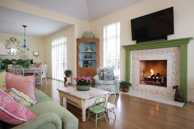 living room featuring a chandelier, wood finished floors, vaulted ceiling, and a tile fireplace