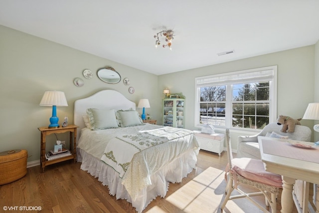 bedroom with visible vents, baseboards, and wood finished floors