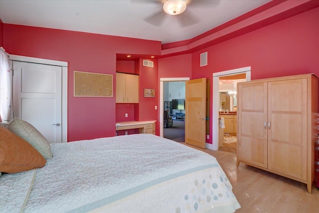 bedroom featuring ensuite bathroom, light wood finished floors, visible vents, and a ceiling fan