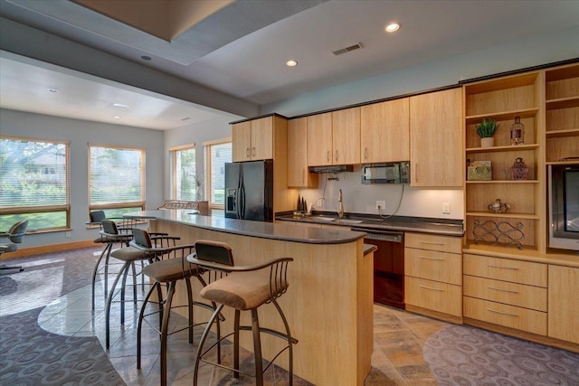 kitchen with a center island, visible vents, light brown cabinets, black appliances, and a kitchen breakfast bar