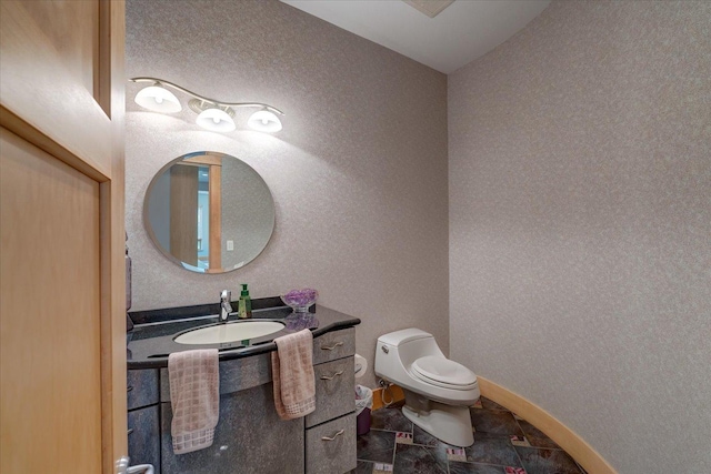 half bathroom with baseboards, a textured wall, vanity, and toilet