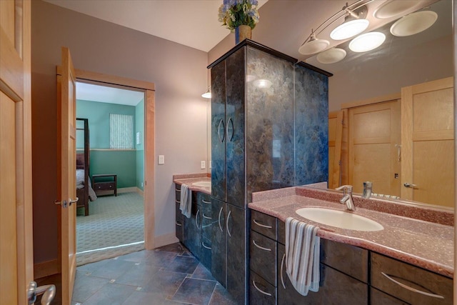 ensuite bathroom featuring connected bathroom, vanity, and baseboards