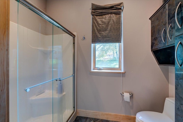 full bath with toilet, a stall shower, and baseboards