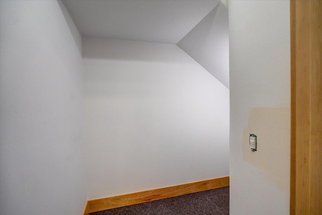 bonus room featuring vaulted ceiling, dark carpet, and baseboards