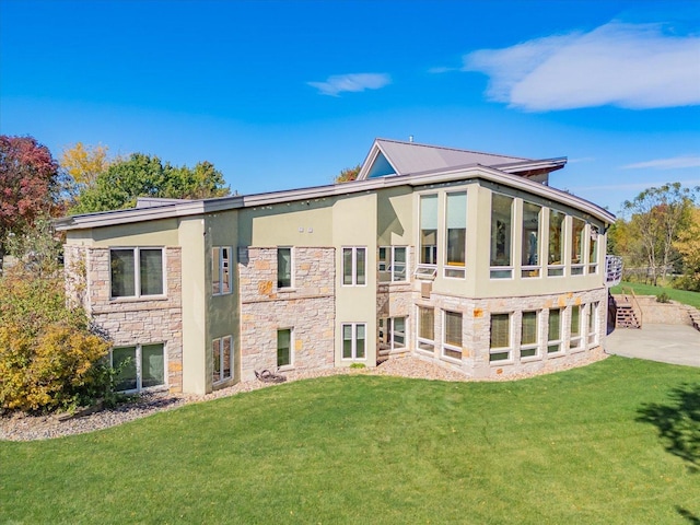 back of house featuring stone siding, a lawn, and stucco siding