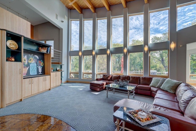 living area with a towering ceiling, wooden ceiling, a wealth of natural light, and beamed ceiling